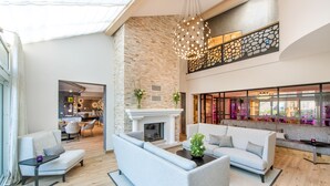 A spacious living area with a fireplace, modern furniture, and a view of the city through large windows.