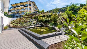 A hotel courtyard with a small pond, wooden deck, and a landscaped garden.