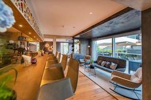 Un interior moderno con una larga mesa de comedor, asientos cómodos y amplios ventanales con vistas.