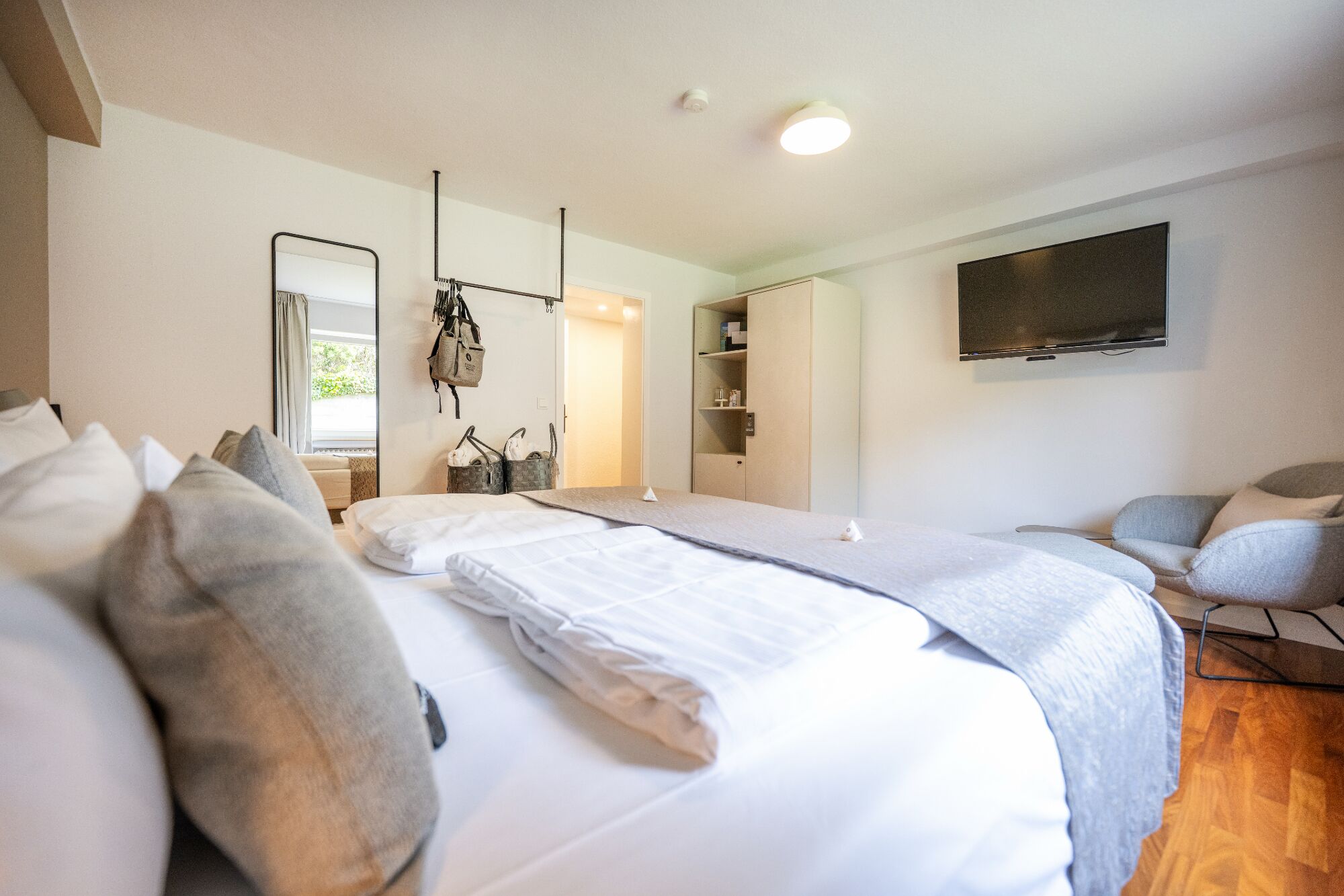 A hotel room with a bed, a TV, a chair, and a wardrobe.
