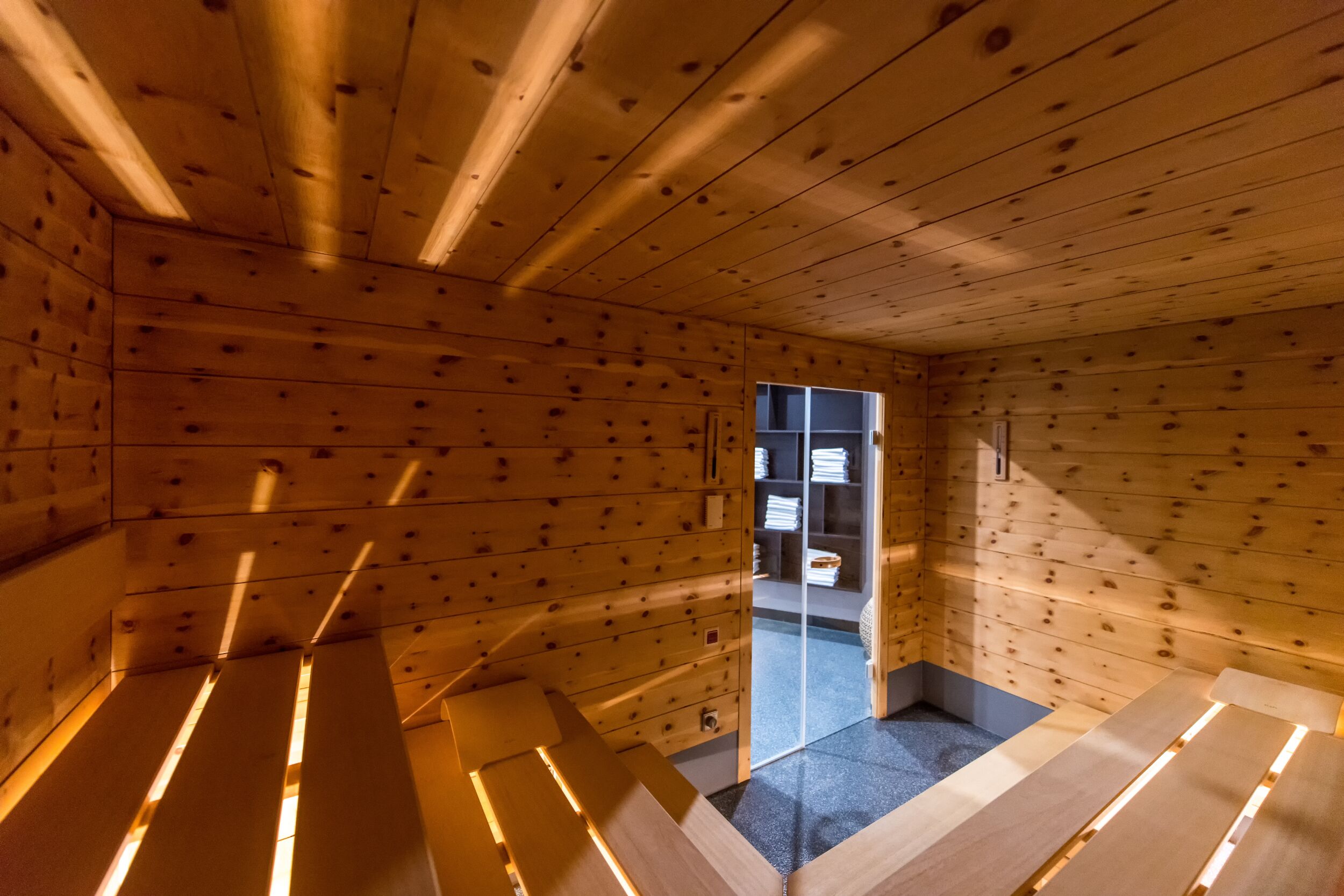 Un intérieur en bois avec un banc, une porte donnant sur l’extérieur et une petite table.