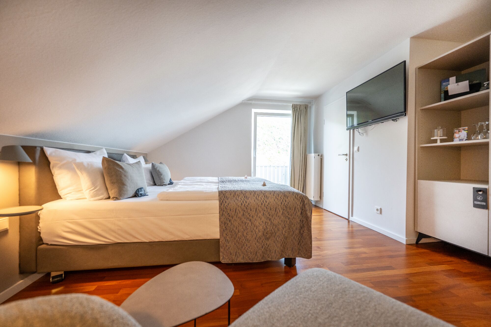 A bedroom with a bed, bedside tables, a TV, and a wardrobe.