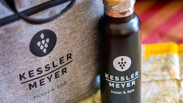 A Kessler Meyer Hotel & Spa bag, a black water bottle with a wooden lid, and a map on a striped surface.