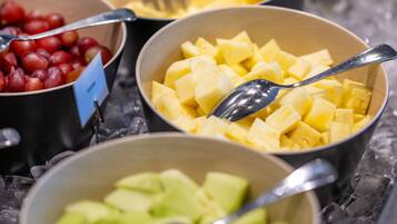 A buffet with various fruits and a spoon in each bowl.