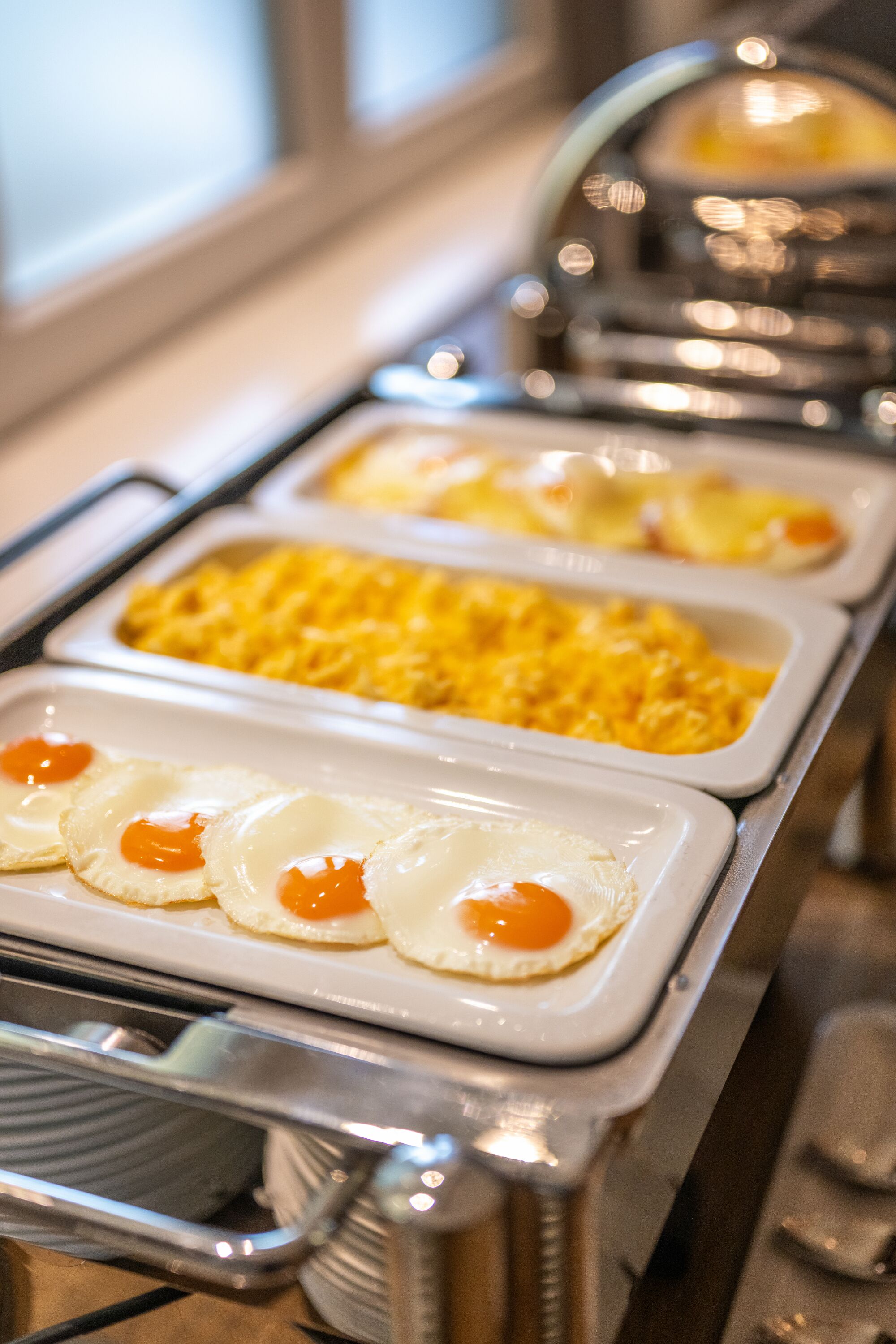A buffet setup with various food items including scrambled eggs and a covered area likely for hot beverages.