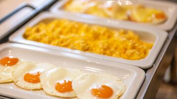 A buffet setup with various food items including scrambled eggs and a covered area likely for hot beverages.
