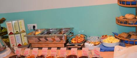 Buffet com diversas opções de comida, incluindo frutas, doces e patês.