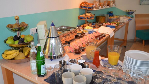A buffet table with various food items, beverages, and dining ware. - Hotel Aquamarin (Papenburg)