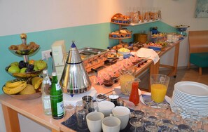 A buffet table with various food items, beverages, and dining ware. - Hotel Aquamarin (Papenburg)