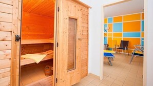 A wooden sauna room with a bench and a small table. - Hotel Aquamarin (Papenburg)