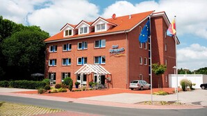 A hotel with a red brick facade, multiple windows, and a sign indicating it is a hotel. - Hotel Aquamarin (Papenburg)