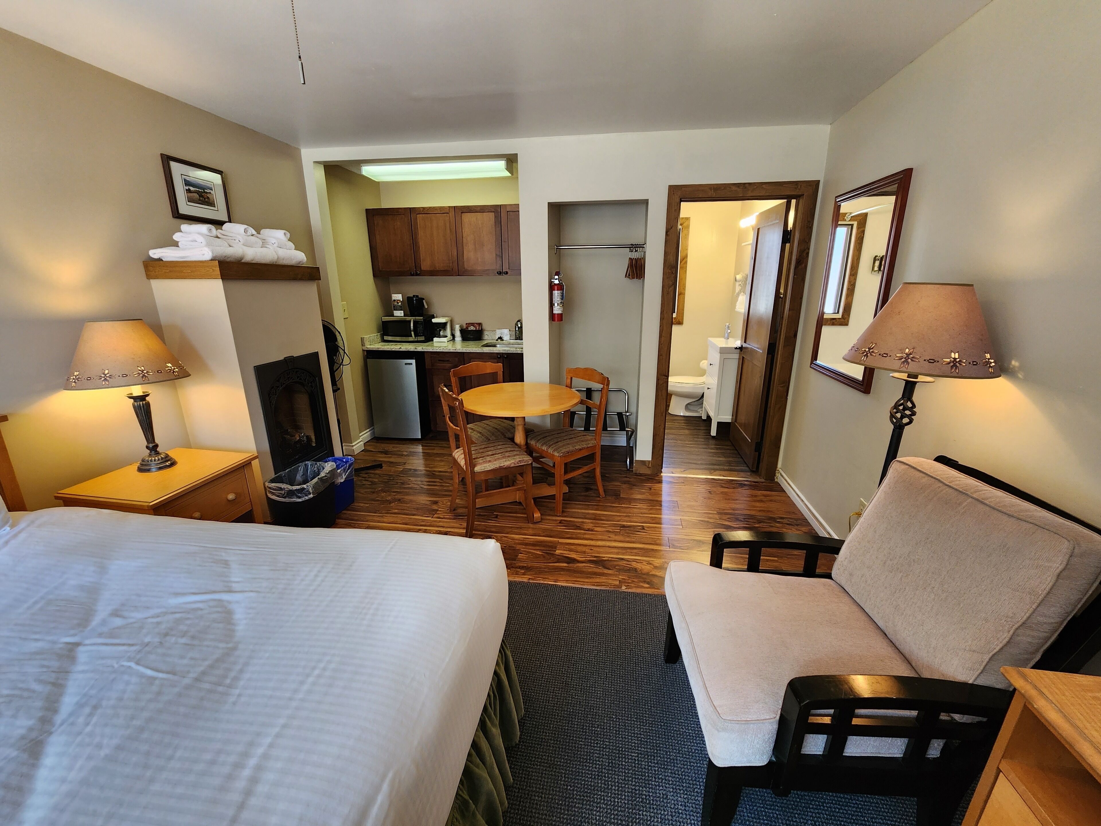Ett hotellrum med en säng, en soffa, ett matbord med stolar, ett litet kök och ett badrum som syns genom en  öppen dörr.
