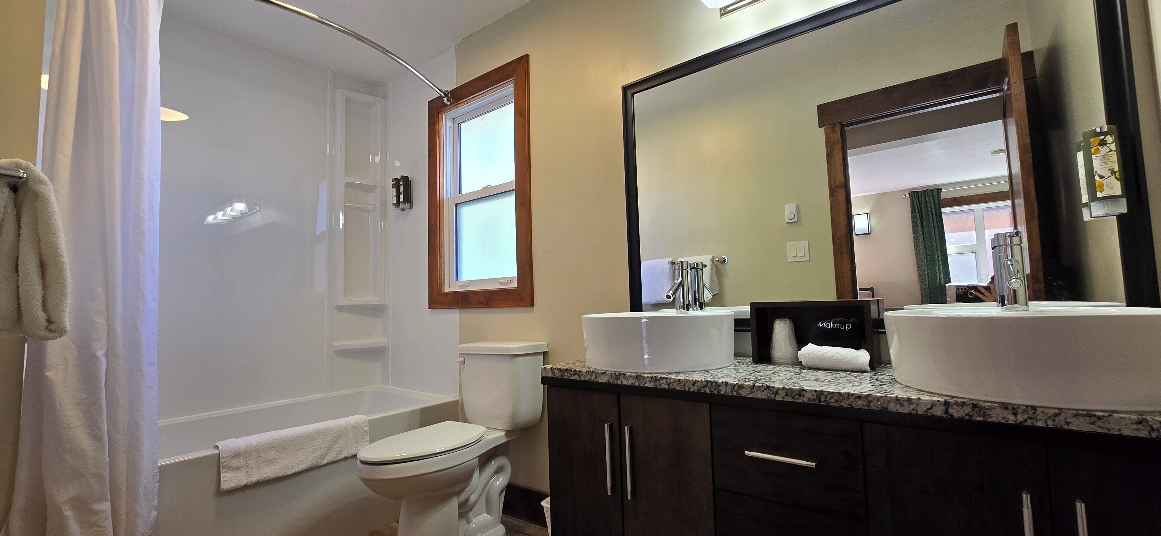 Een badkamer met een bad, toilet en twee wastafels.