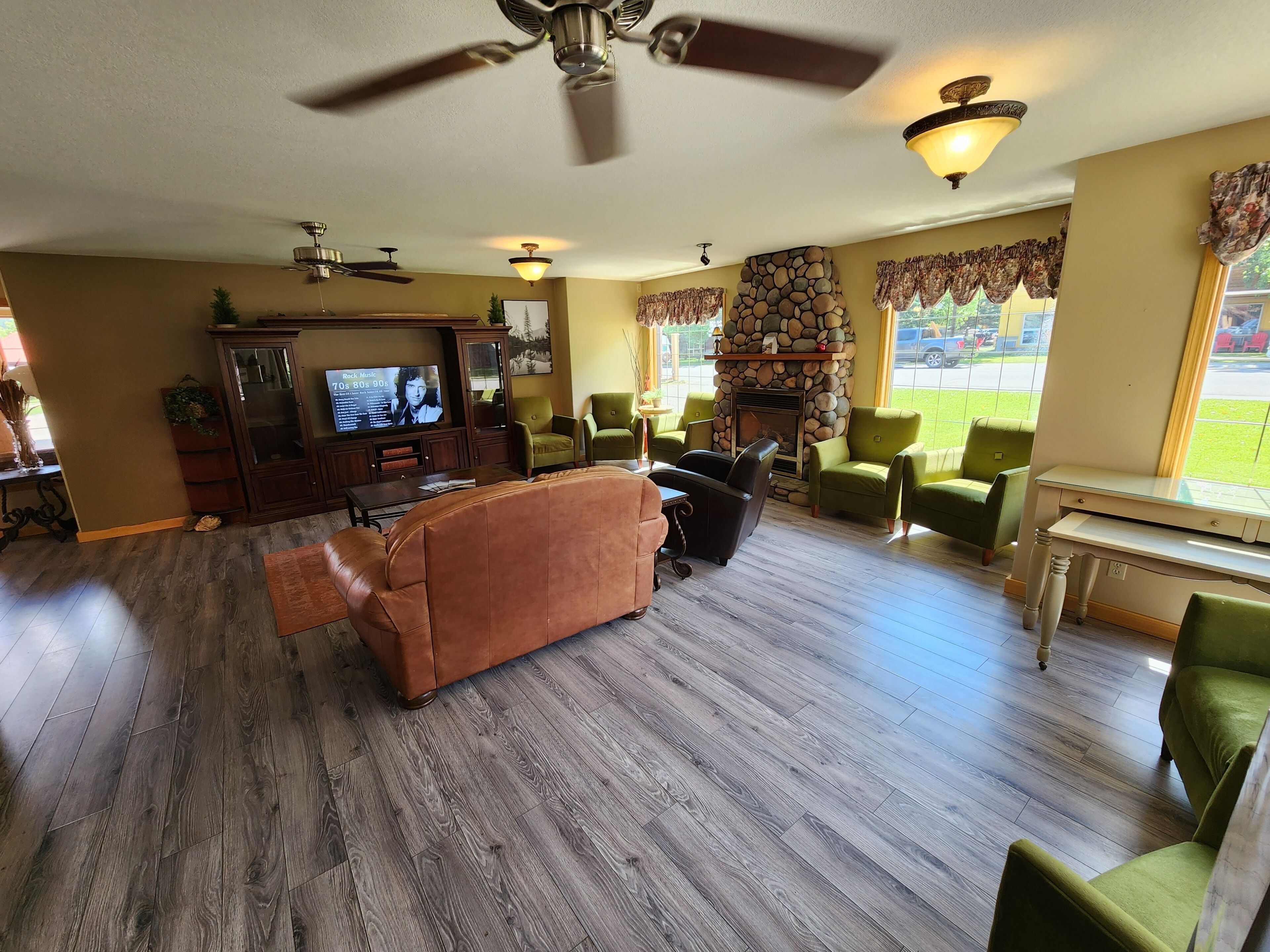 A living room with a fireplace, green chairs, a brown sofa, and a television.