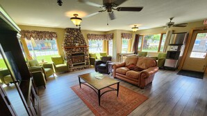A spacious living room with a fireplace, green armchairs, a leather sofa, and a coffee table. - Aspen Village Inn (Waterton Park)