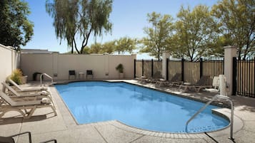 Una piscina al aire libre, sillones reclinables de piscina