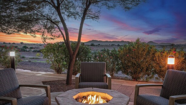 A fire pit surrounded by wicker chairs, set against a backdrop of a sunset over a desert landscape. - Courtyard Phoenix Chandler/Fashion Center (Chandler)