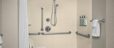 A modern bathroom with a walk-in shower, grab bars, a toilet, and a towel rack.