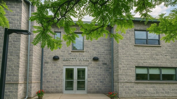 Un edificio de piedra con un letrero que dice "BEATTY HALL" y una entrada con dos puertas.