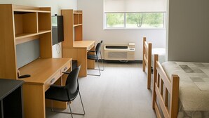Un dormitorio moderno con escritorio, sillas, cama y ventana.