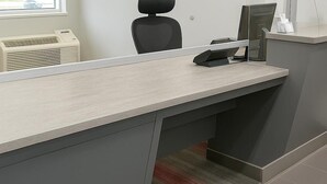 Una mesa de recepción con un teléfono, una computadora y un mostrador pequeño.