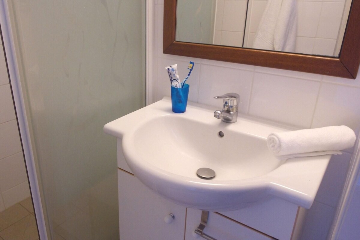 A bathroom with a white sink, a mirror, and a towel.