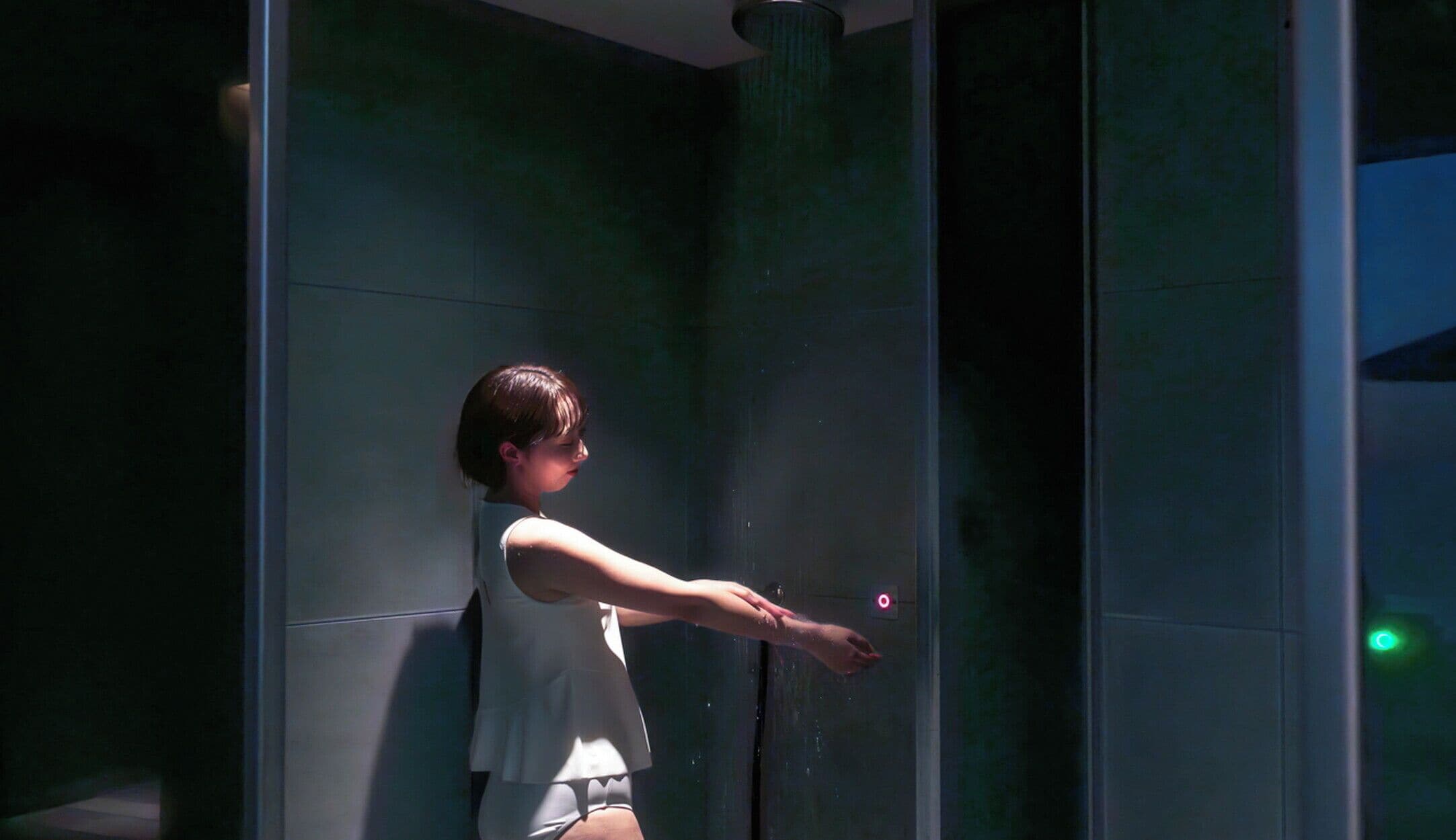 A person in a modern bathroom with a glass shower enclosure.