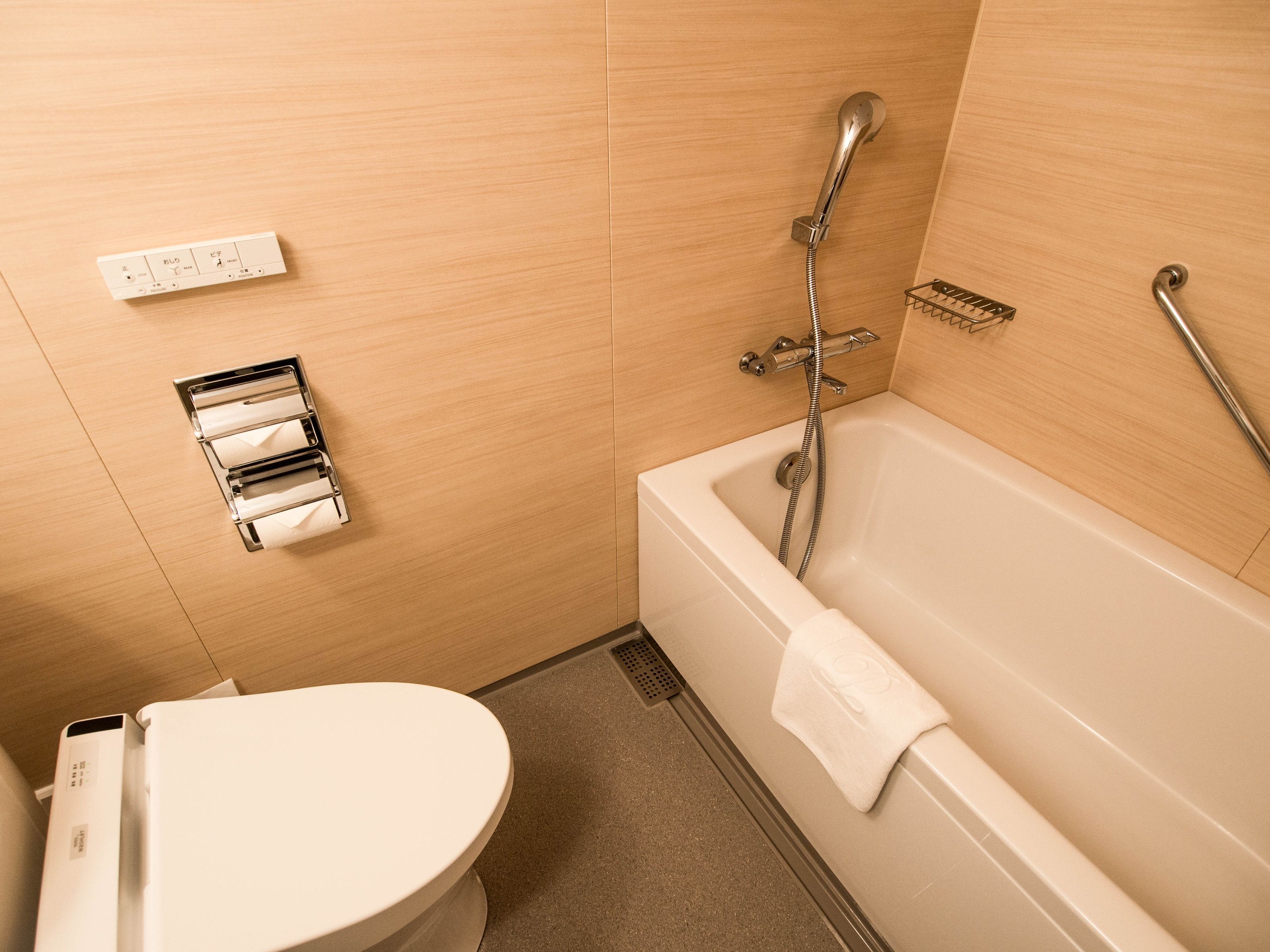 A bathroom with a bathtub, toilet, and a towel rack.