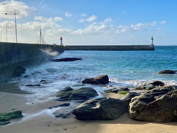 A coastal scene with a lighthouse, rocky shoreline, and calm sea.
