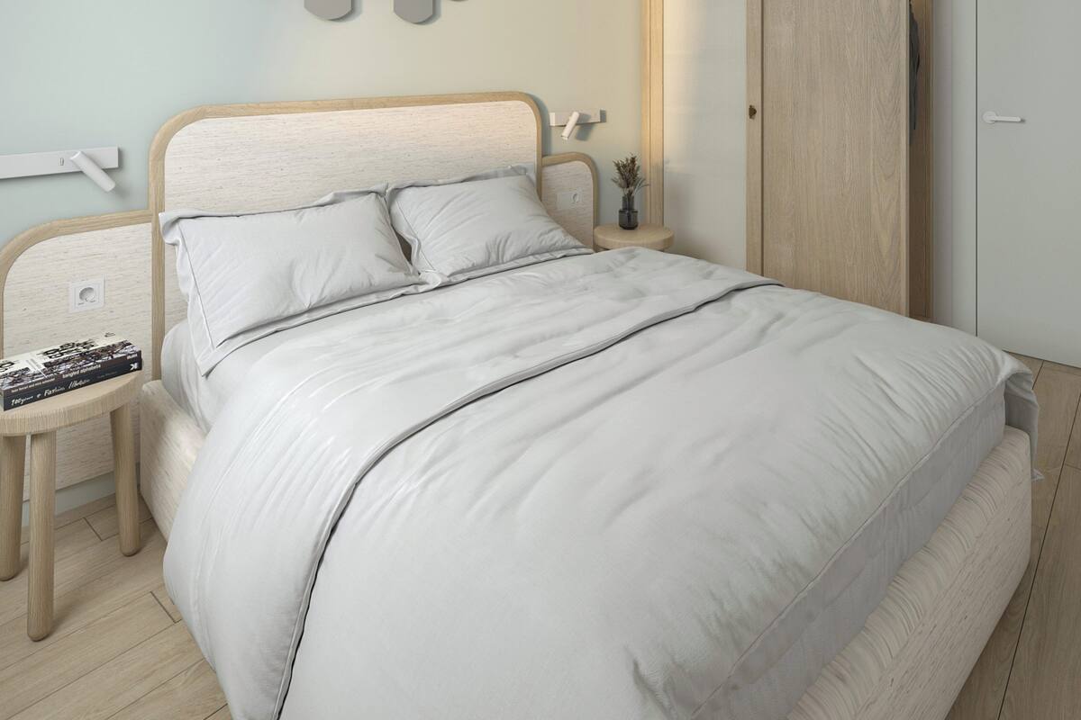 Ein Schlafzimmer mit einem Bett, Nachttischen, einem Kleiderschrank und einer Wandleuchte.