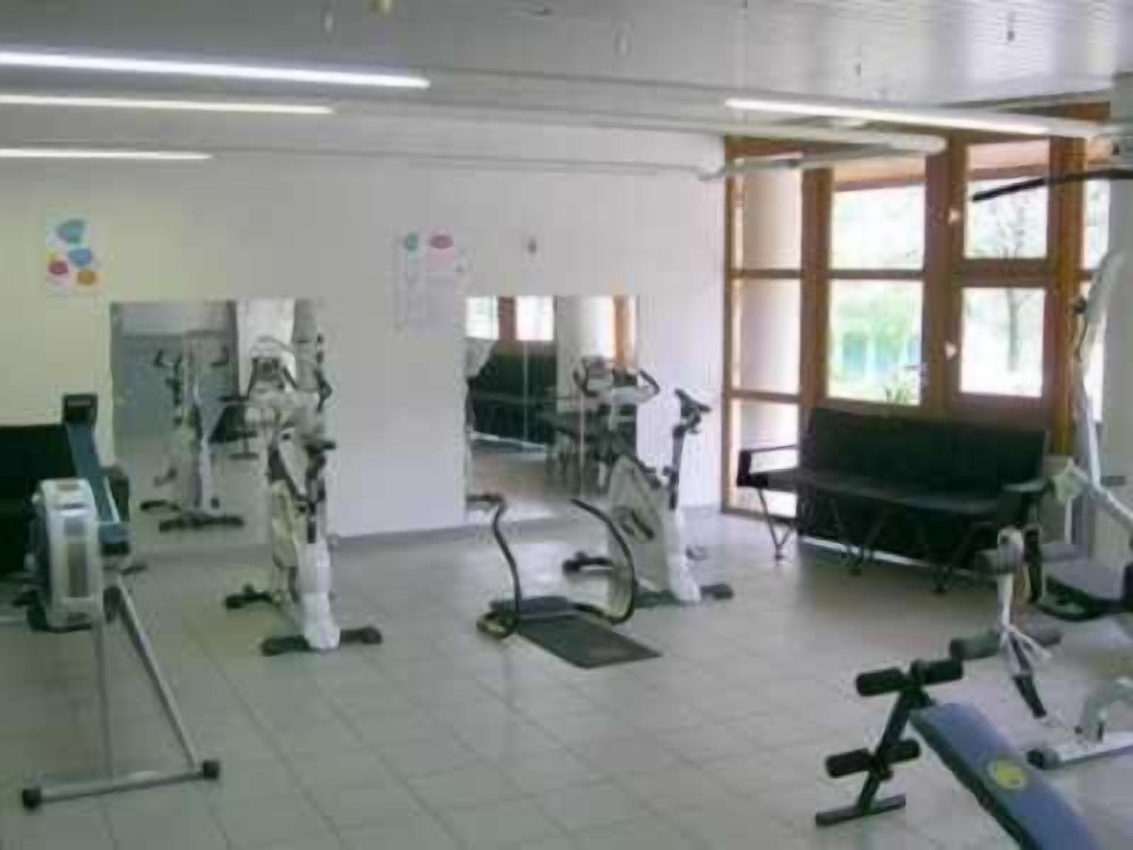 Un gimnasio con varios equipos de ejercicio, incluyendo cintas de correr y bicicletas estáticas.