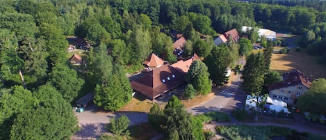 An aerial view of a residential area with multiple houses, a small river, and a bridge.
