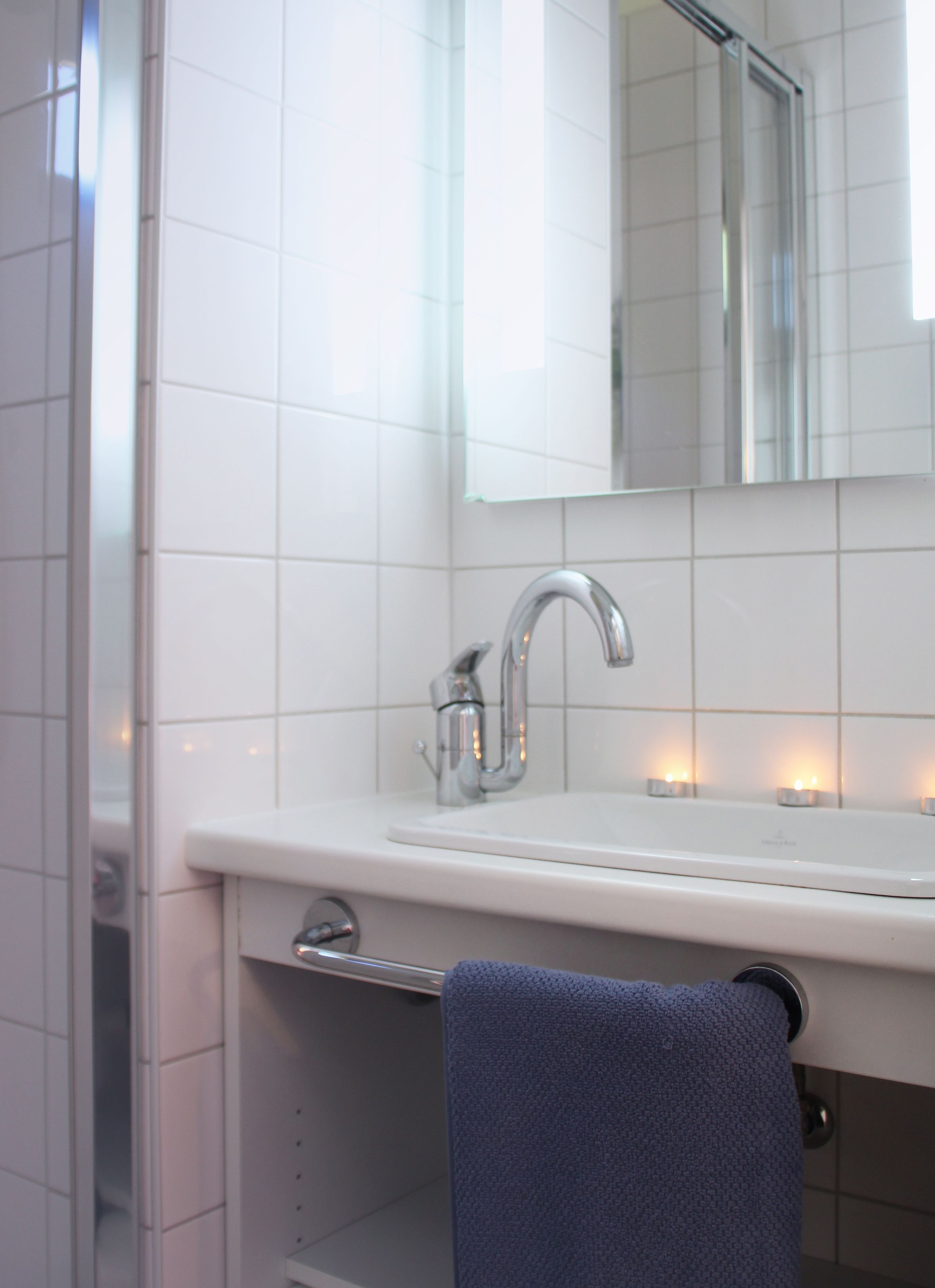A bathroom with a white sink, a mirror above it, and a towel hanging on a rack.