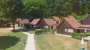 A row of modern, brown-roofed cabins with a central pathway leading through a well-maintained lawn. - VVF Les Vosges Bitche (Bitche)