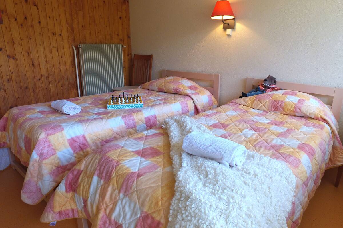 Ein Hotelzimmer mit zwei Betten, einem Schachbrett und einem Stuhl.
