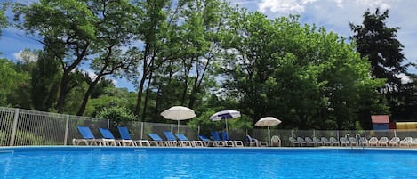 Una piscina al aire libre, sillones reclinables de piscina