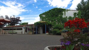 A courtyard with a building covered in ivy, outdoor seating, and potted plants. - VVF Les Gorges de l'Allier, Lavoûte Chilhac (Lavoute-Chilhac)
