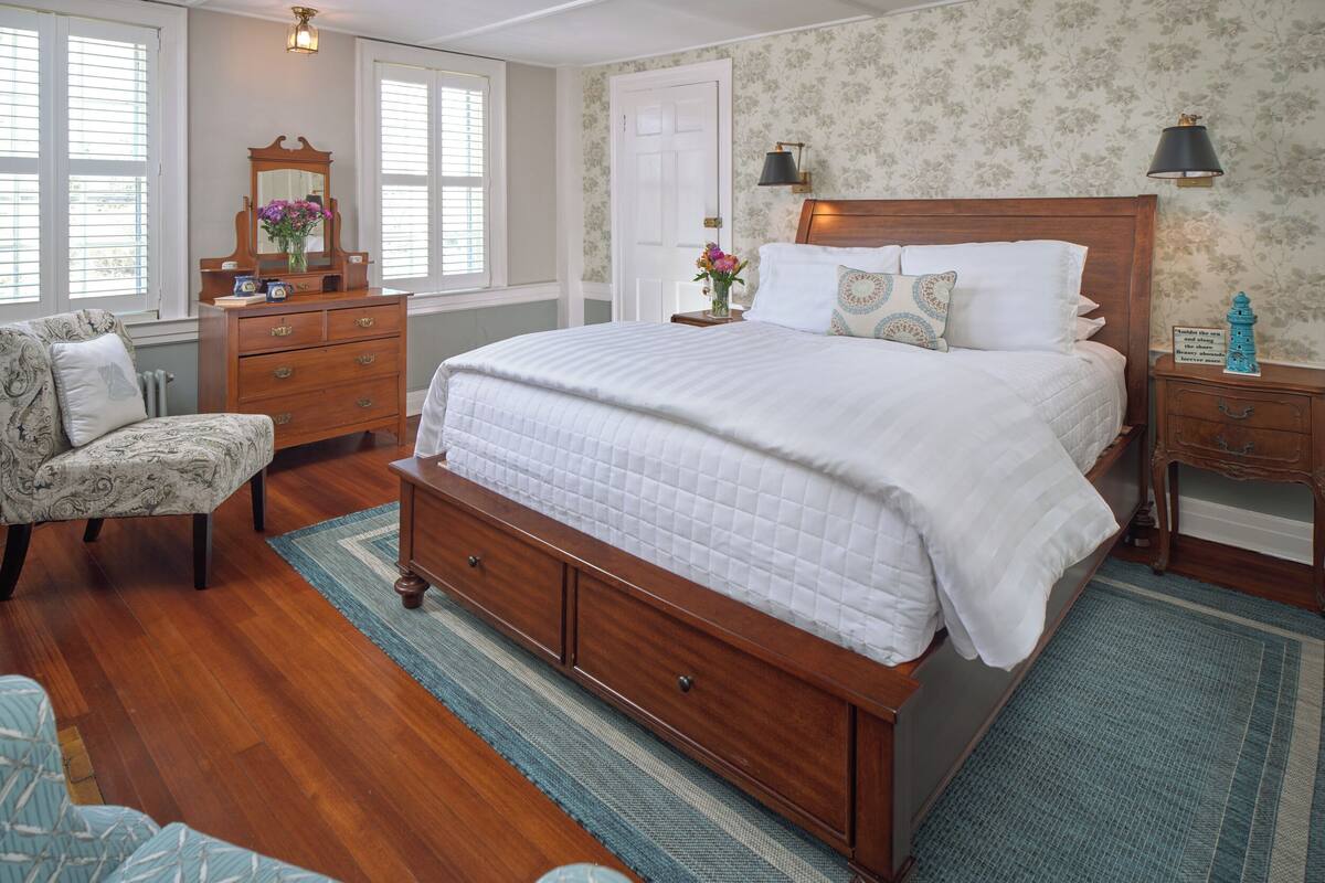 Une chambre à coucher avec un lit en bois, une commode, une chaise et une table de chevet.