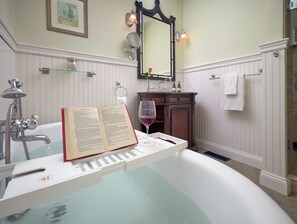 A bathroom with a bathtub, a book, and a wine glass. - The Old Manse Inn (Brewster)
