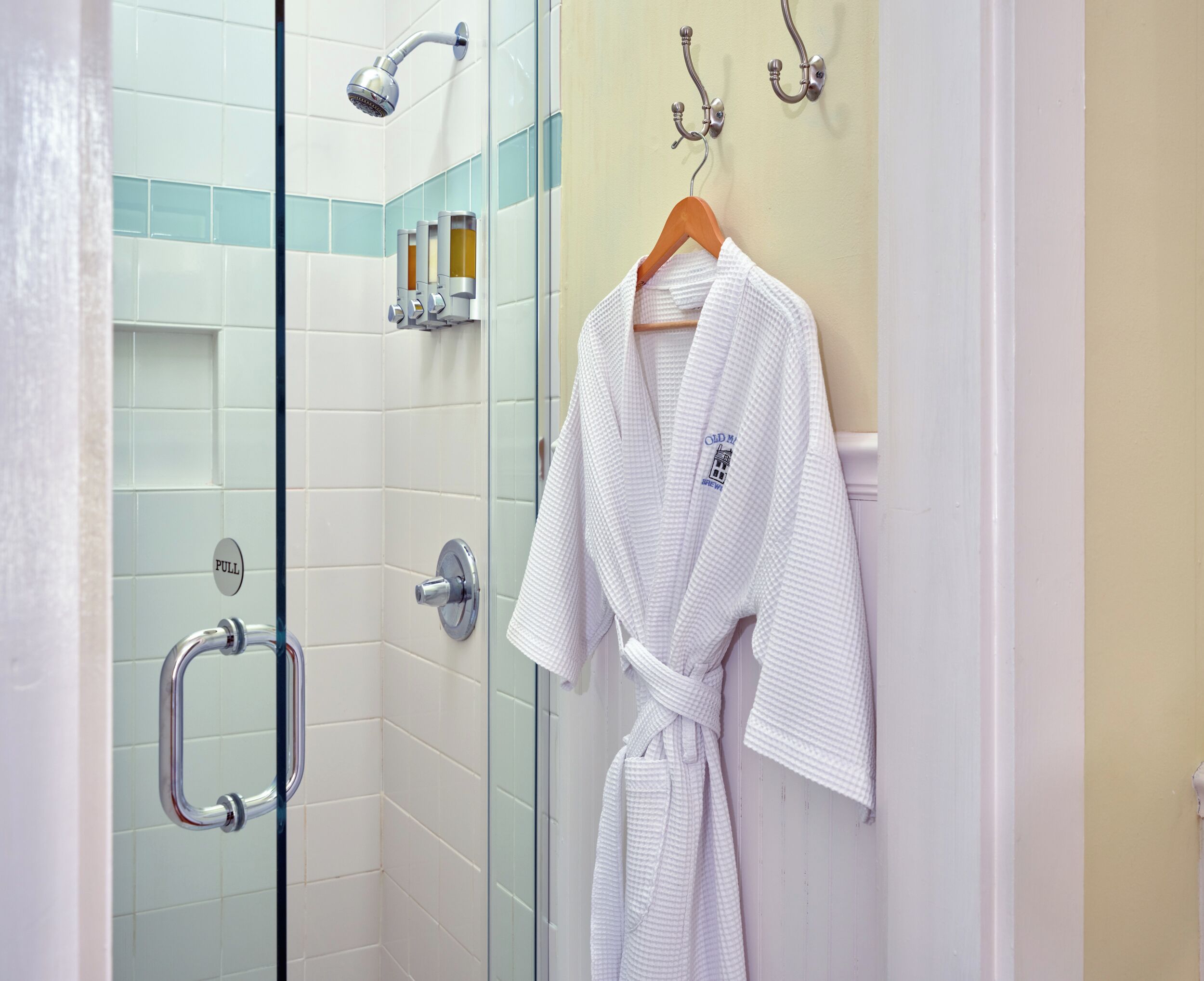 A bathroom with a glass shower enclosure, a towel rack, and a pull handle.
