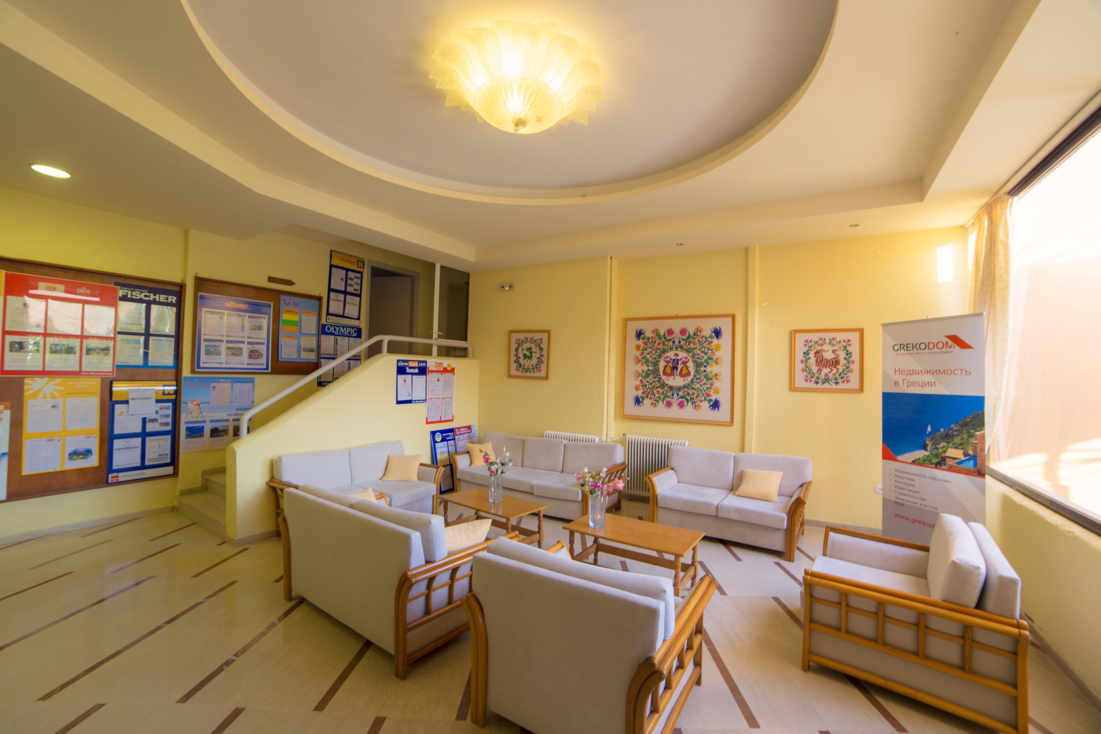 A hotel lobby with a staircase, seating area, and various informational posters on the walls.