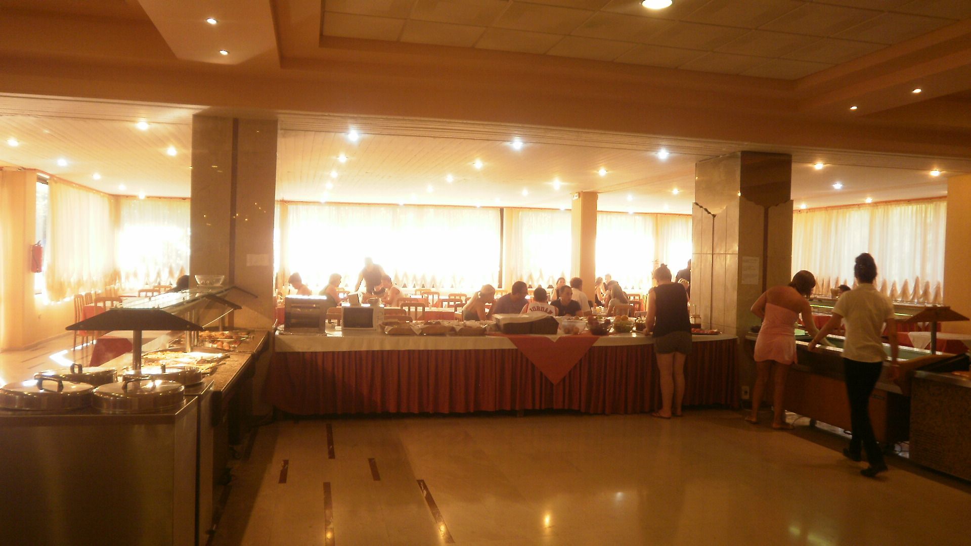 A buffet setup with multiple food stations and a counter where staff are serving.