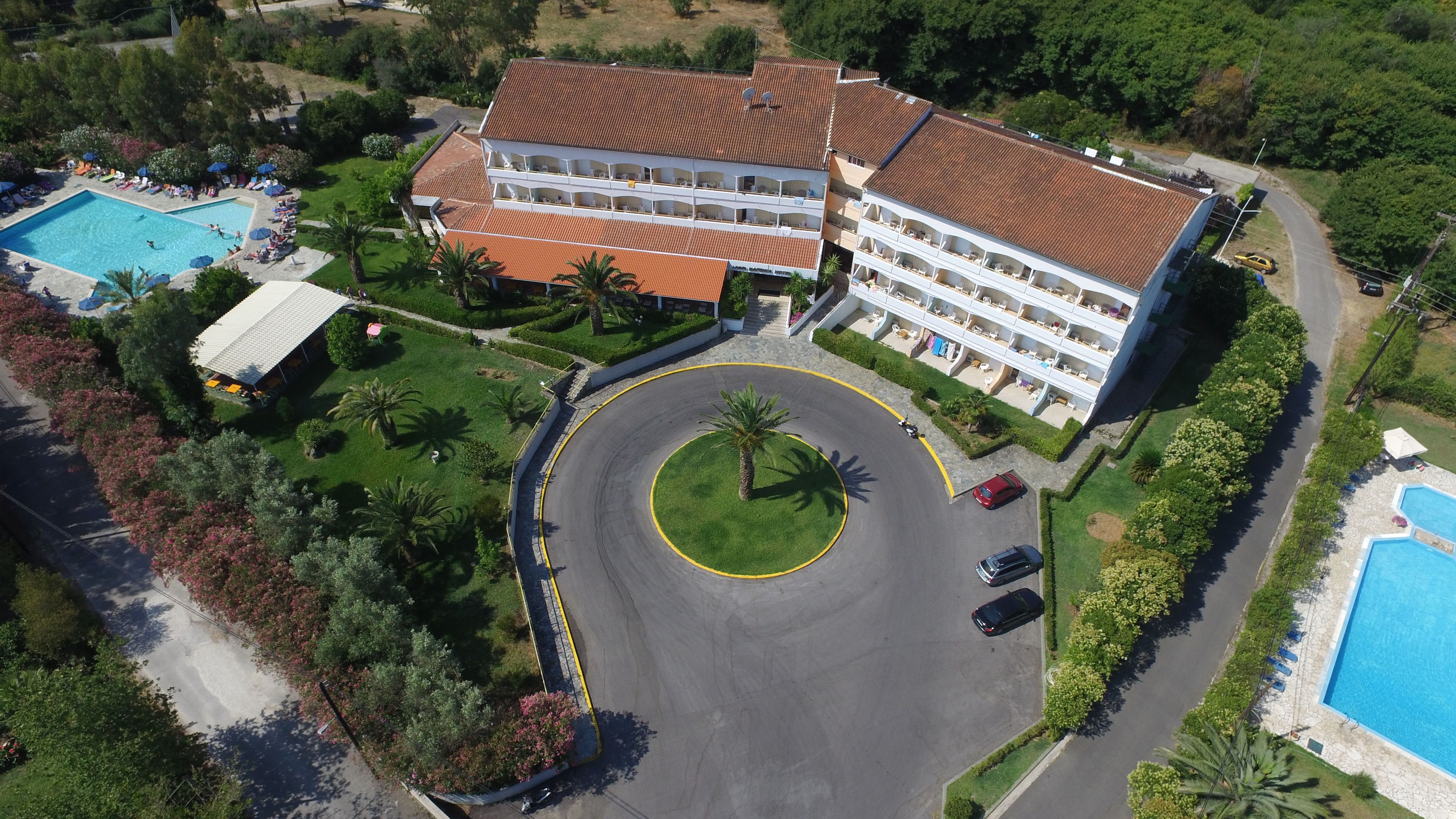 Un hotel de varios pisos con un patio central, piscinas y jardines exuberantes.