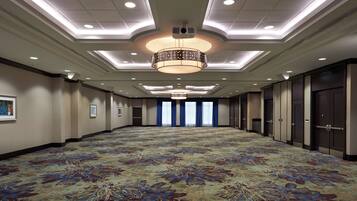 A large, well-lit conference room with a patterned carpet, recessed lighting, and a central chandelier.