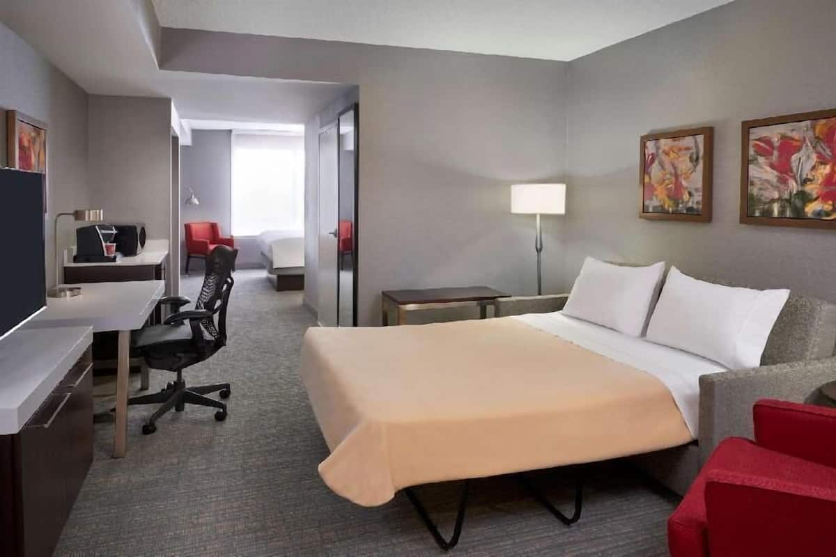 Una habitación de hotel con cama, escritorio, silla y una mesita.