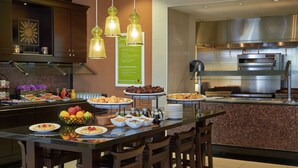 Una cocina moderna con una disposición tipo bufé, que incluye una variedad de alimentos y un horno industrial.