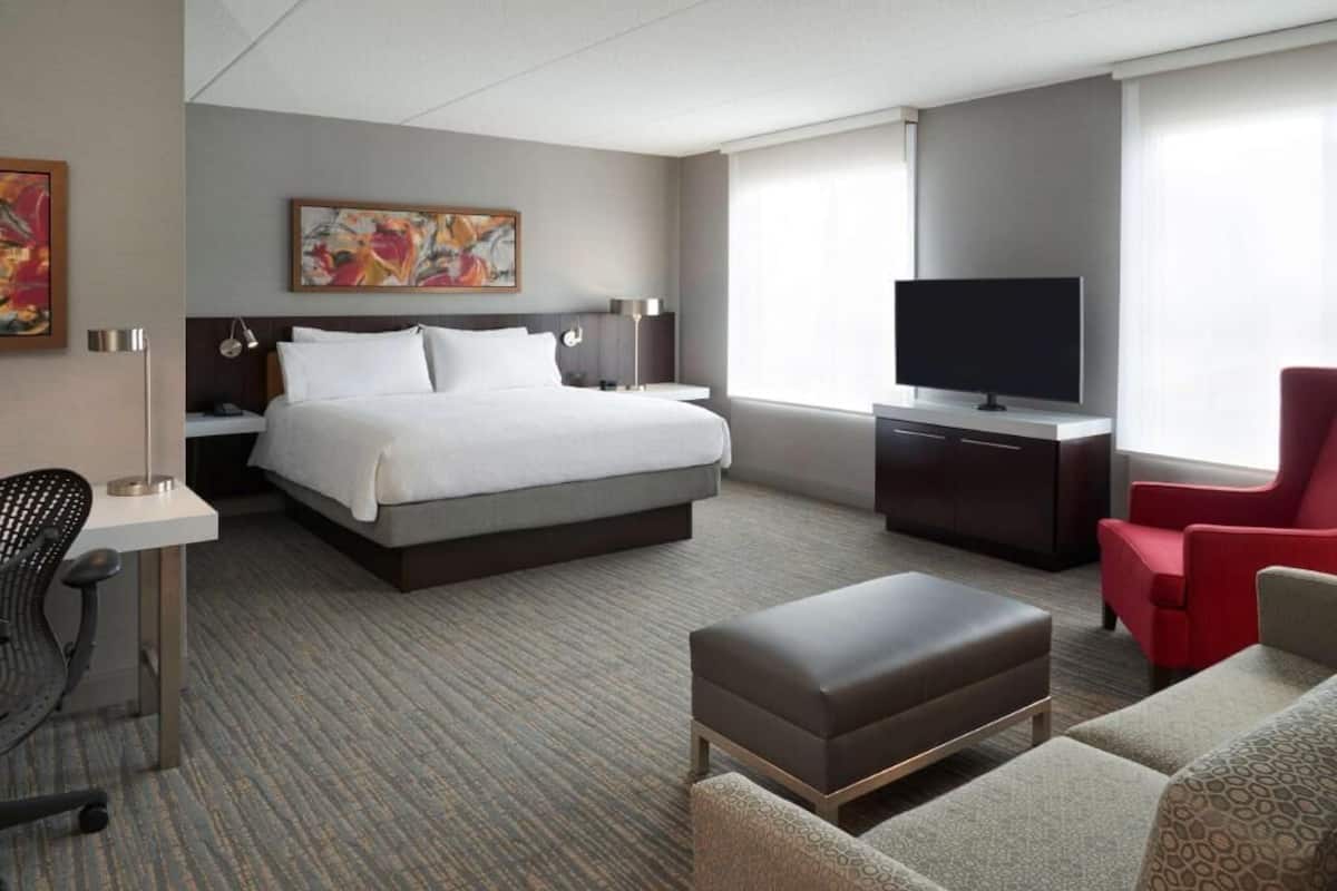 Una habitación de hotel con cama, televisor, escritorio, silla y sofá.