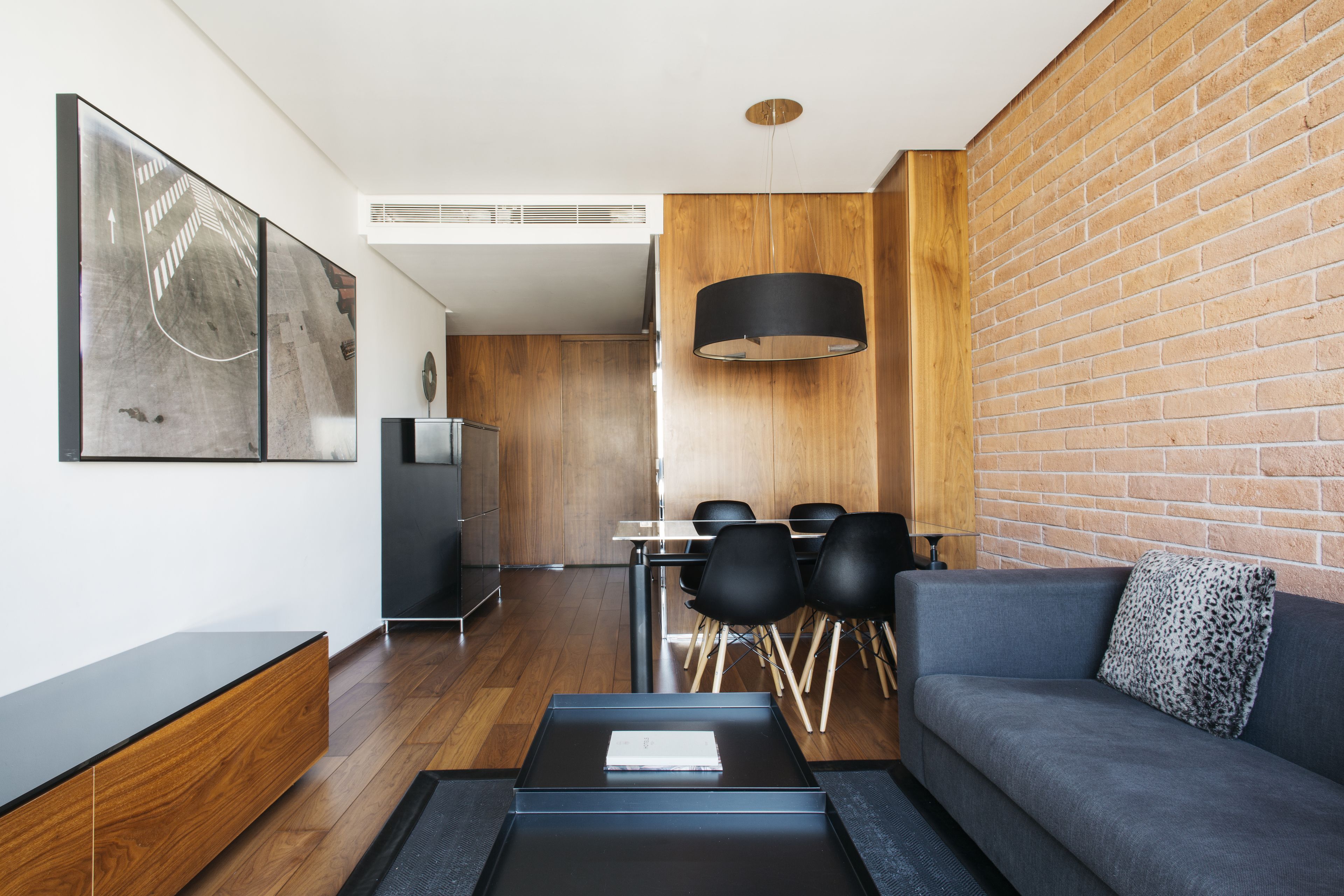Una sala de estar moderna con un sofá gris, una mesa de centro y un comedor con una mesa y sillas.
