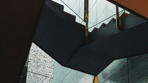 Un interior moderno con una escalera de cristal que baja a un nivel inferior.