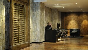 Zona de recepción con mostrador de madera, un sofá de cuero negro y una pared con textura.